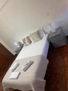 a bedroom with a large white bed with two slippers at Quarto Alameda in Lisbon