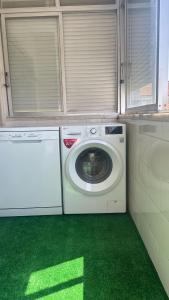 a laundry room with a washing machine and green floor at Quarto Alameda in Lisbon