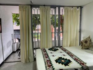 a bedroom with a bed and a large window at loft central, cerca a laureles GUARDA MELETAS GRATIS!! in Medellín