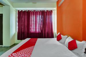 a bedroom with a bed with red walls and a window at OYO Flagship Hotel CDS Regency in Patna