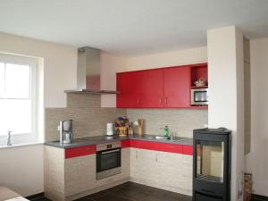 a kitchen with red cabinets and a sink at Ostseebrandung - Haus Seestern in Dranske