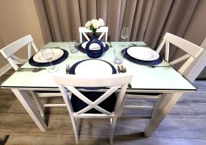 a white table with chairs and a vase with flowers at Beautiful Guesthouse, Sleeps 4 - Kitchen, Private Laundry, AC, Parking, 65' TV, Close to Stores, Restaurants & Beach in Long Beach