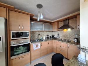 a kitchen with wooden cabinets and a sink at Apartamento full equipado en Lechería in El Morro de Barcelona