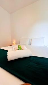 - une chambre avec un grand lit blanc et une couverture verte dans l'établissement Pousada Enero, à Maragogi