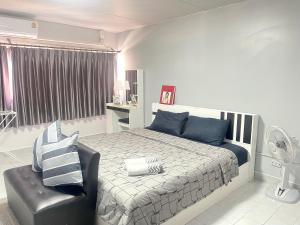 a bedroom with a bed and a black chair at Lovely Impact C3-C9 Lily in Nonthaburi