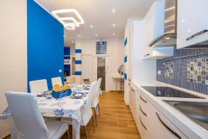 une cuisine avec une table, des chaises blanches et un mur bleu dans l'établissement Bianca Azzurra, à Finale Ligure