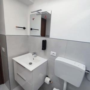 uma casa de banho branca com um lavatório e um espelho em Casa vacanze La Bonta' di Palermo em Palermo