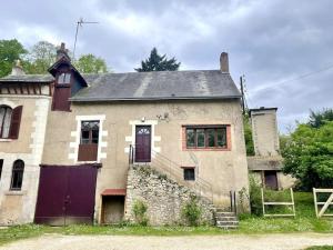 uma velha casa de pedra com uma porta roxa em Gite du Meunier, au bord du Cosson, 4 étoiles em Vineuil