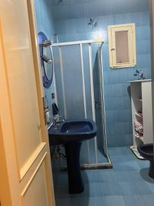 y baño azul con lavabo y ducha. en Casa vacanze San Cassiano Salento, en San Cassiano