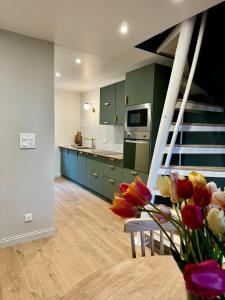 a kitchen with green cabinets and a vase of flowers at L'Adresse - Rempart Sud - Eguisheim avec garage privé in Eguisheim +27 photos