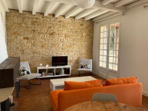 特雷莫拉的住宿－LES HAUTS DE TREMOLAT，客厅配有橙色家具和砖墙