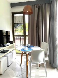 a dining room with a table and white chairs at Condado Aldeia dos Reis in Mangaratiba