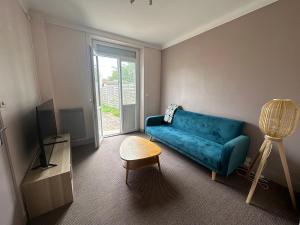 a living room with a blue couch and a window at Le Cabieu in Ouistreham