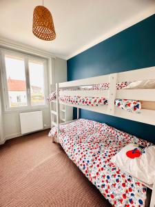 a bedroom with two bunk beds and a blue wall at Le Cabieu in Ouistreham