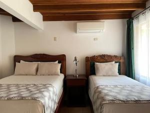 - 2 lits installés l'un à côté de l'autre dans une chambre dans l'établissement Hotel Javy, à Liberia