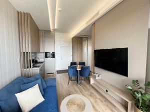 a living room with a blue couch and a tv at Shellter Premium Przy Wydmie in Rogowo