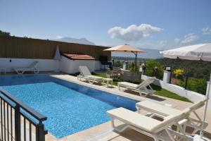 a swimming pool with lounge chairs and an umbrella at HYVillaS HÜMA in Muğla