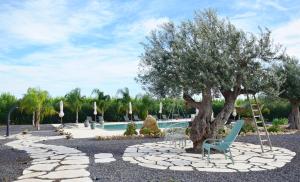 a swing under a tree next to a pool at Antico Casale Benalì in Siracusa