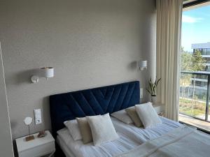 a bed with a blue headboard in a bedroom with a window at Shellter Premium Przy Wydmie in Rogowo