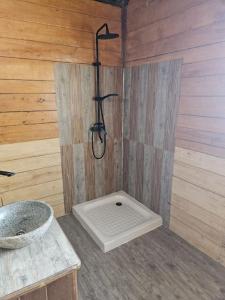 a bathroom with a shower in a wooden wall at Villa Tropicale Fy in Mahajanga