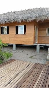 a house with a straw roof and a wooden deck at Villa Tropicale Fy in Mahajanga