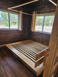 a wooden bed in a room with two windows at Villa Tropicale Fy in Mahajanga