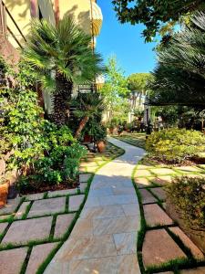 a stone walkway with palm trees and a building at Hotel Giardino in Lido di Camaiore
