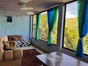 a living room with a couch and a table and windows at Spacious Cloud Studio Mandango Vista in Loja