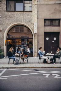 a group of people sitting at tables on a sidewalk at Old Town Apartment Black in Bratislava