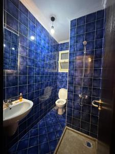 W wyłożonej niebieskimi kafelkami łazience znajduje się toaleta i umywalka. w obiekcie Porto El Sokhna Aqua park w mieście Ajn Suchna