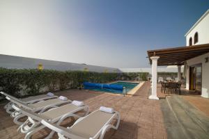 um grupo de espreguiçadeiras ao lado de uma piscina em Sophisticated Lanzarote Villa | Villa Mervella | 4 Bedrooms | Spacious Terrace Area & Private Pool | Playa Blanca em Playa Blanca