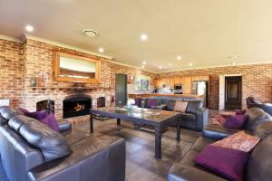 a living room with leather furniture and a fireplace at The Lodge - Ironstone Estate Hunter Valley in Lovedale