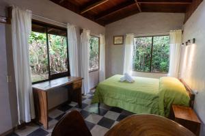 sypialnia z łóżkiem, biurkiem i oknami w obiekcie El Bosque Trails & Eco-Lodge w mieście Monteverde