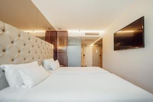 a bedroom with two beds and a tv on the wall at ABC Hotel Porto - Boavista in Porto