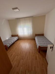 two beds in a large room with wooden floors at Vikendica Lazic in Ljubovija