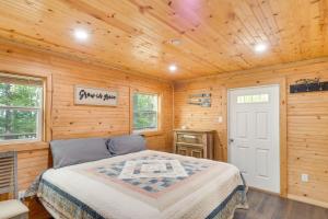 een slaapkamer met een bed in een houten kamer bij Cozy Hemphill Cabin with Lake Views and Deck! in Hemphill