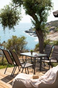 a table and chairs on a deck with a view of the ocean at Acroterra - Easy Living in Alyki