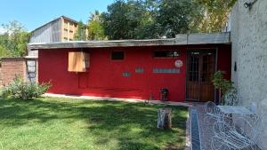 ein rotes Haus mit einer roten Tür im Hof in der Unterkunft El Parralito in Mendoza