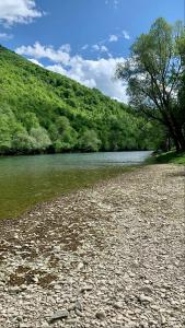 a river with a rocky shore next to a mountain at 069 Riverside Vikendica - Banja Luka in Rekavice