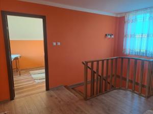 orangefarbenes Zimmer mit einer Treppe und einer Glastür in der Unterkunft Cabana din șes in Mărişel
