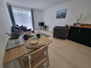 a living room with a table with plates on it at Waterfront Retreat - Modern Apartment in Burnham on Crouch