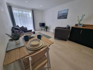 a living room with a table with plates on it at Waterfront Retreat - Modern Apartment in Burnham-on-Crouch