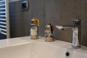 un lavandino in bagno con rubinetto e due bottiglie di sapone di La Finestra Blu Alba 1 ad Alba Altre 18 foto