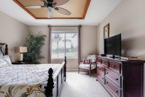 a bedroom with a bed and a flat screen tv at Five Star Waikoloa Beach Villa, Golf & Lake Views in Waikoloa