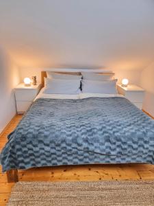 a large bed with a blue comforter and two lamps at Ferienhaus Heckler in Bad Camberg