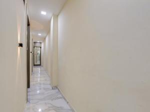 OYO HOTEL KING View في أحمد آباد: ممر به جدران بيضاء وأرضية من الرخام