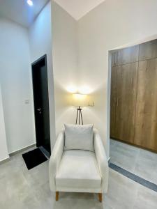 une chaise blanche dans une chambre avec une lampe dans l'établissement Skypark One Gulberg - Apartments by Superhost, à Islamabad