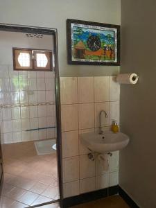 a bathroom with a sink and a shower with a painting at Maasaifari Moshi 36 in Moshi