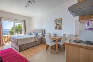 a bedroom with a bed and a table and a kitchen at Apartments Gudelj in Podgora