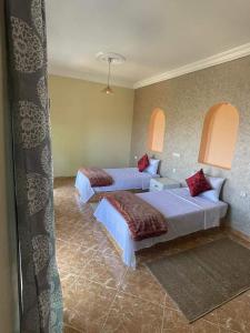 a hotel room with two beds and two windows at dar hamra in Mejlaou